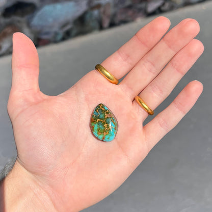 A polished golden spiderweb turquoise cabochon from Manassa, Colorado.