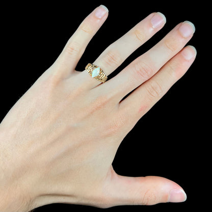 A ladies' yellow gold diamond-cut ring prong set with a natural, marquise cut white opal stone.