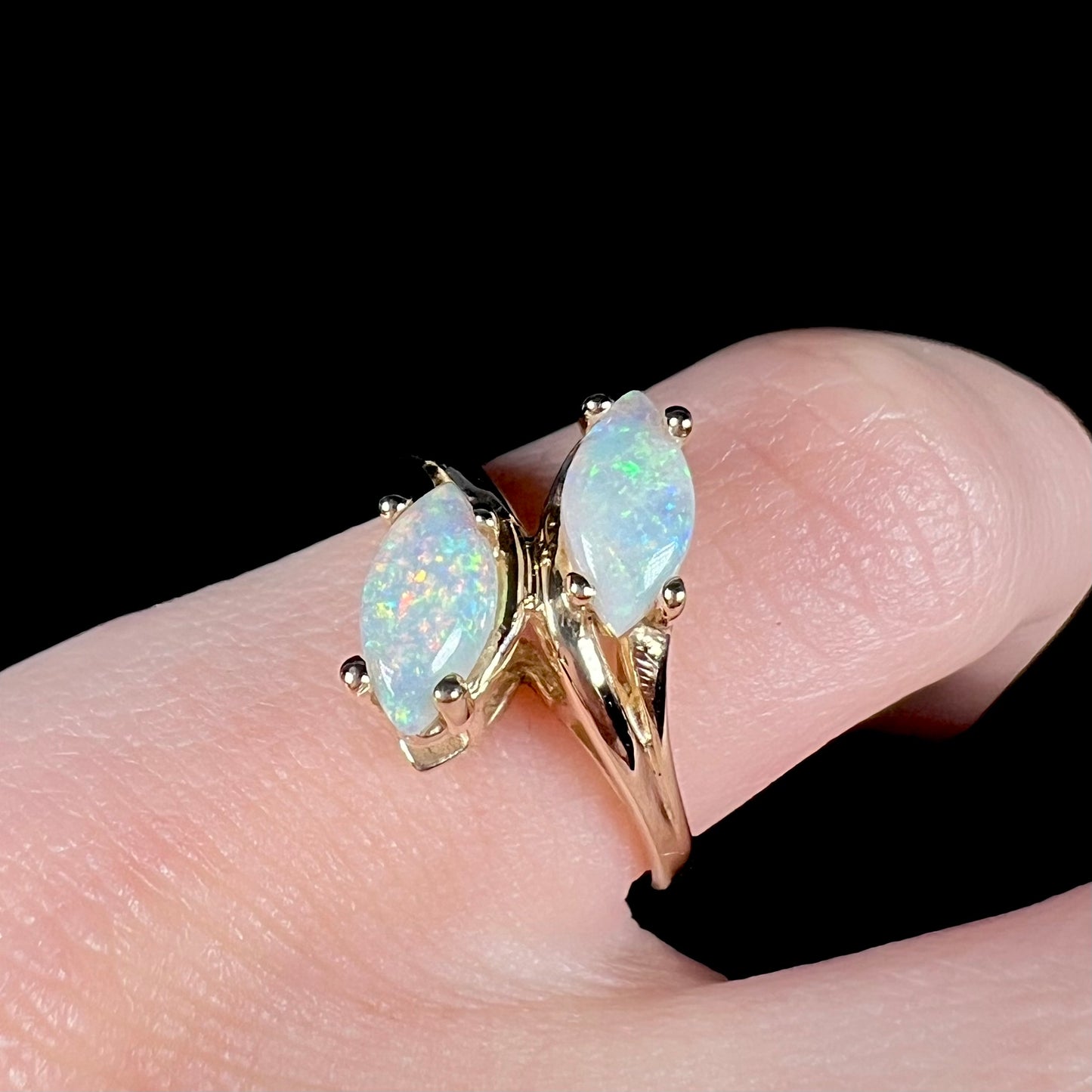 A yellow gold ring mounted with two prong-set marquise cut opal cabochons.