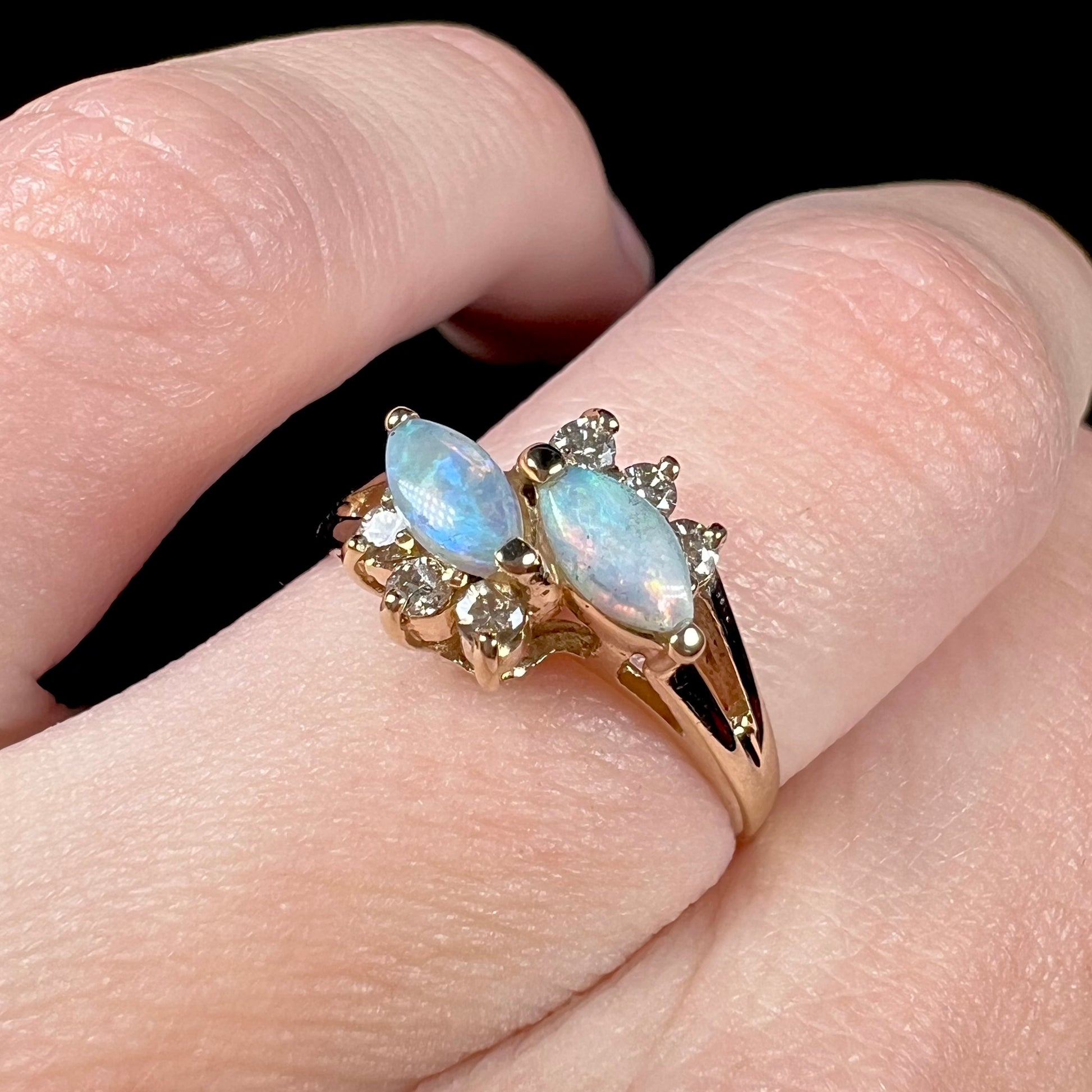 A yellow gold ring mounted with two marquise cut opals and accented with six round diamonds.