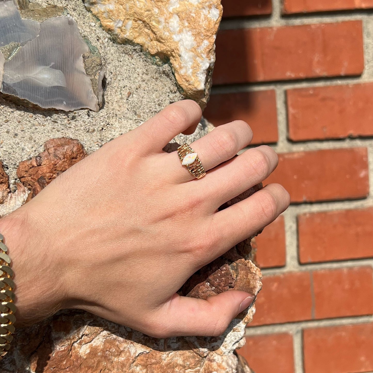 A ladies' yellow gold diamond-cut ring prong set with a natural, marquise cut white opal stone.