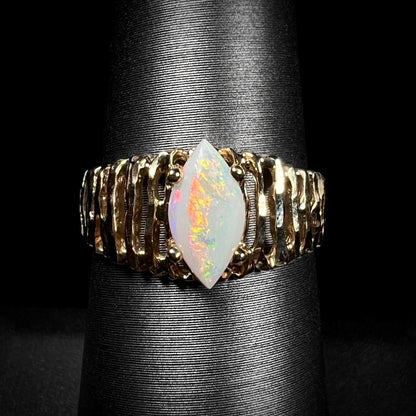 A ladies' yellow gold diamond-cut ring prong set with a natural, marquise cut white opal stone.