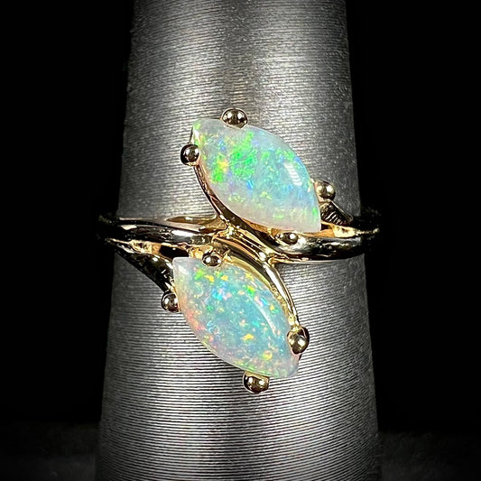 A yellow gold ring mounted with two prong-set marquise cut opal cabochons.