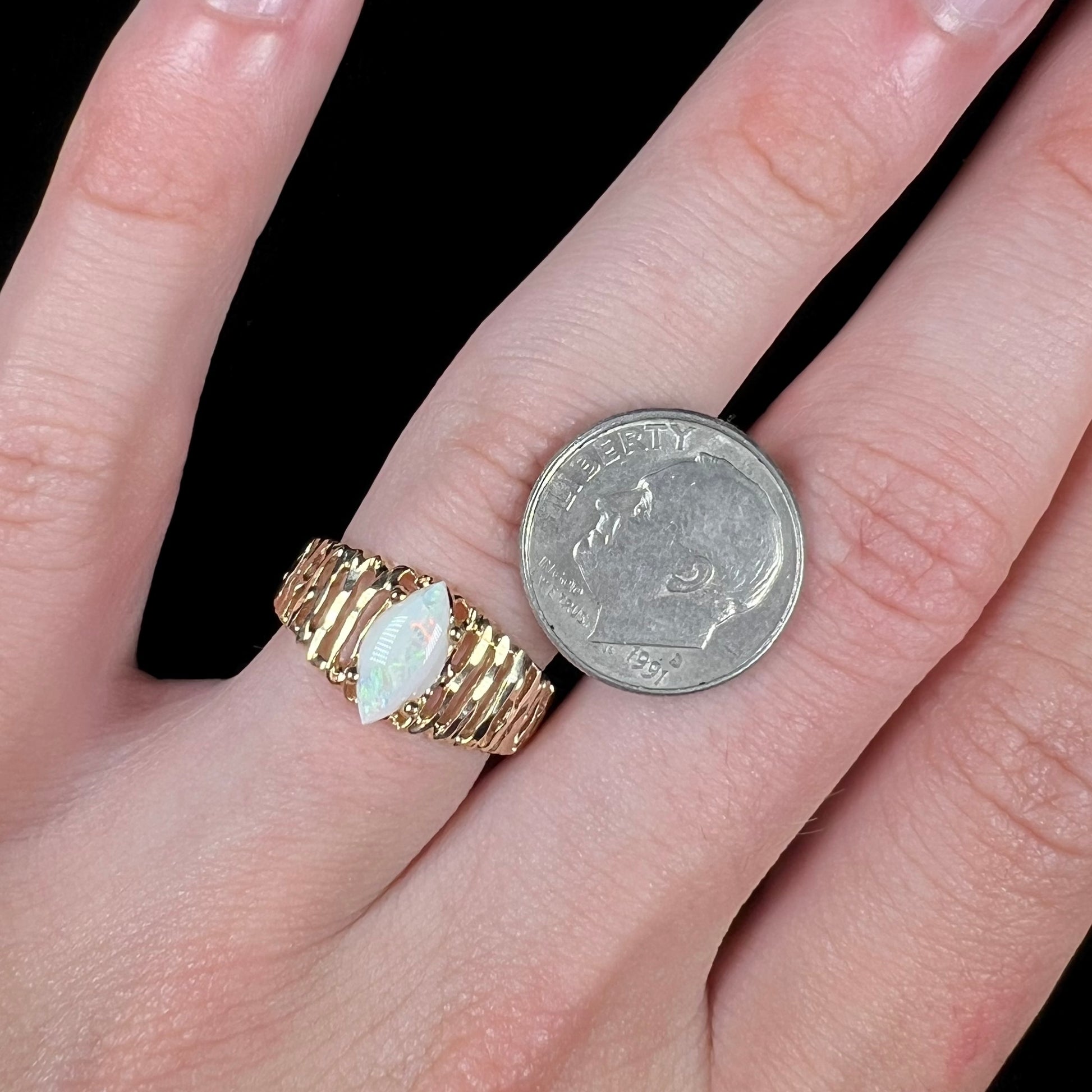 A ladies' yellow gold diamond-cut ring prong set with a natural, marquise cut white opal stone.