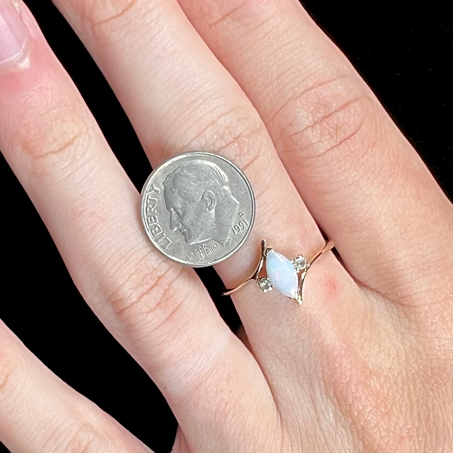 A yellow gold marquise cut opal ring set with two white sapphire accent stones.