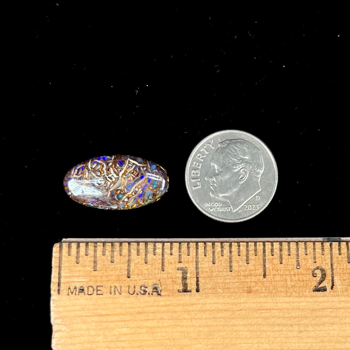 An oval cabochon cut Koroit boulder matrix opal stone.  The opal has blue colors.