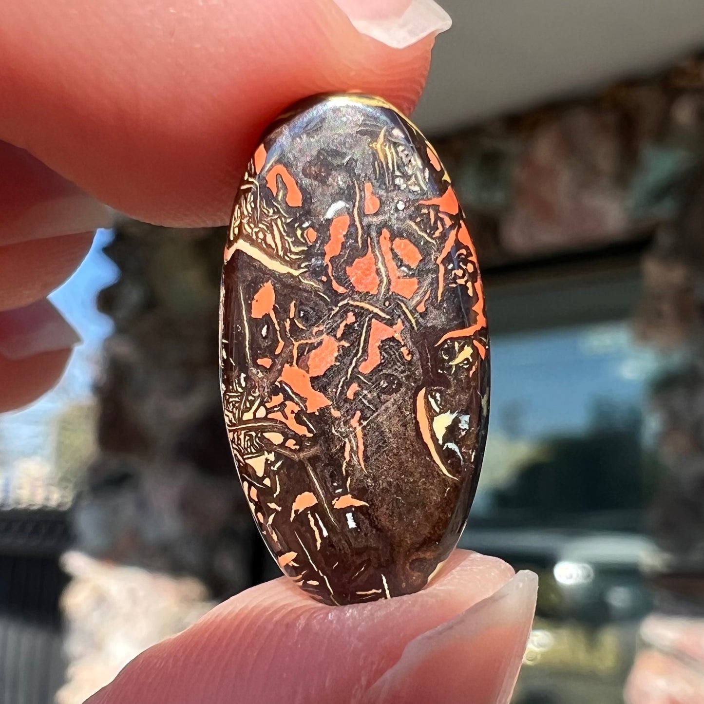 An oval cabochon cut Koroit boulder matrix opal stone.  The opal has blue colors.