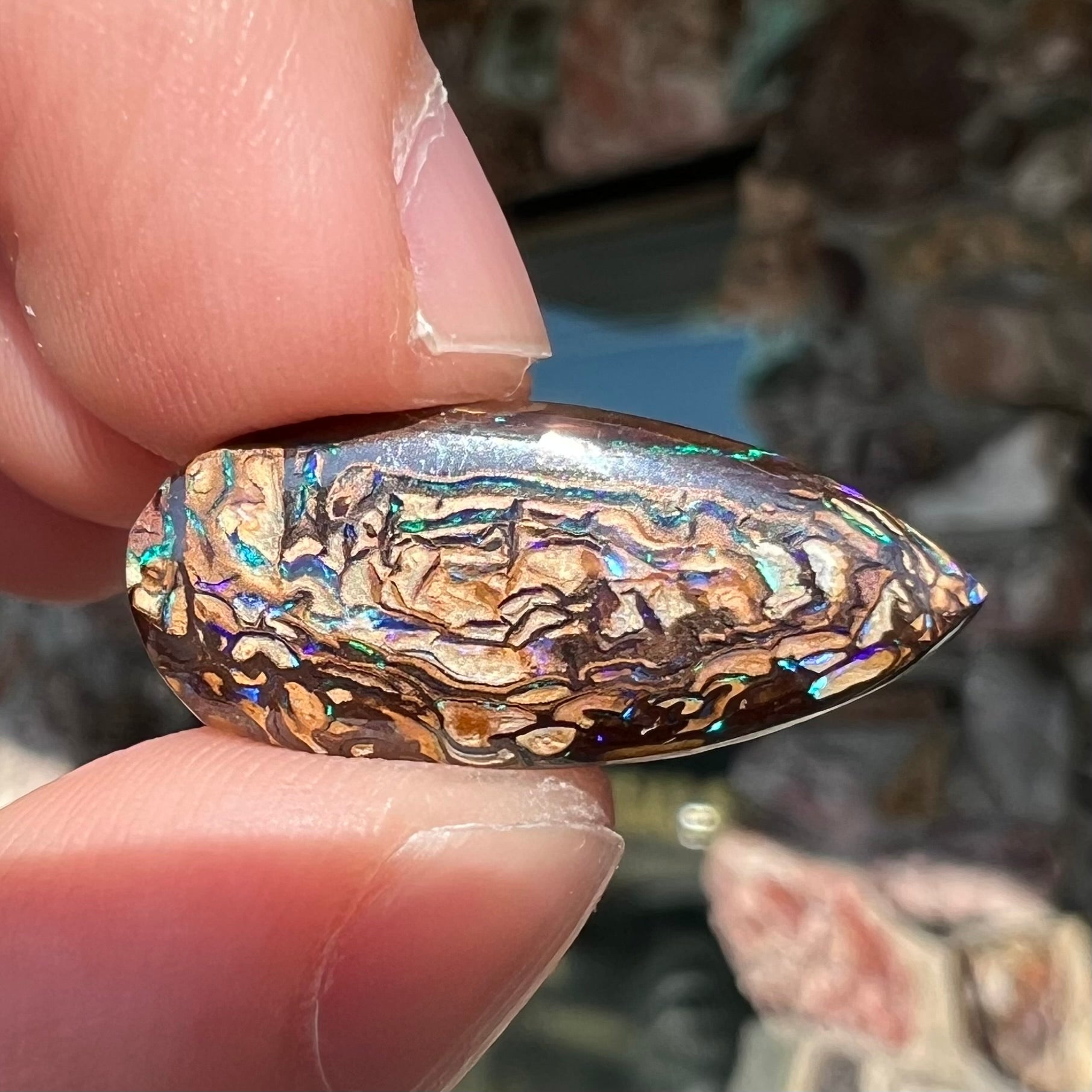 A pear shaped Koroit boulder matrix opal with blue and purple colors in veins.