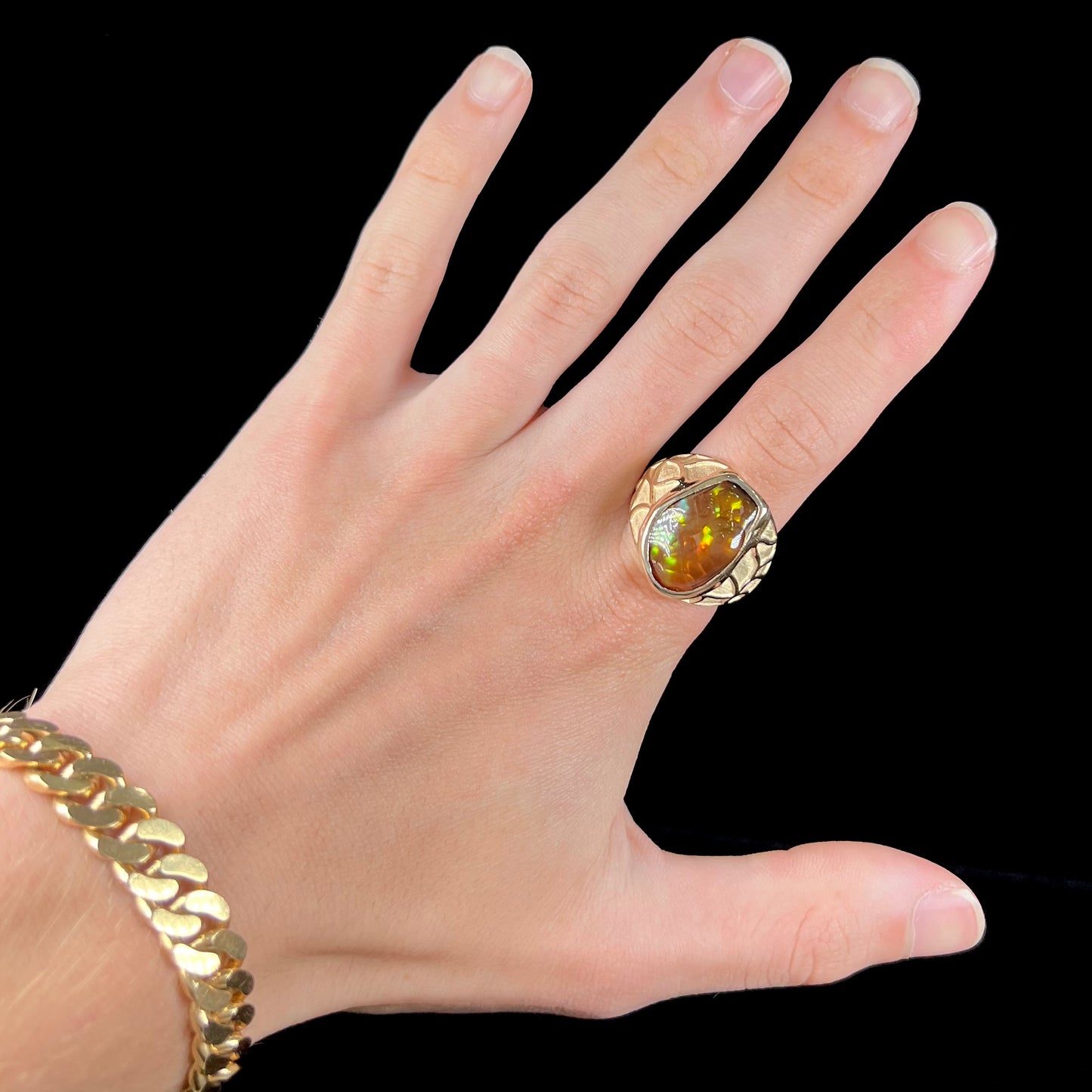 A men's heavy yellow gold ring mounted with a Mexican fire agate stone.  The shank of the ring is textured.