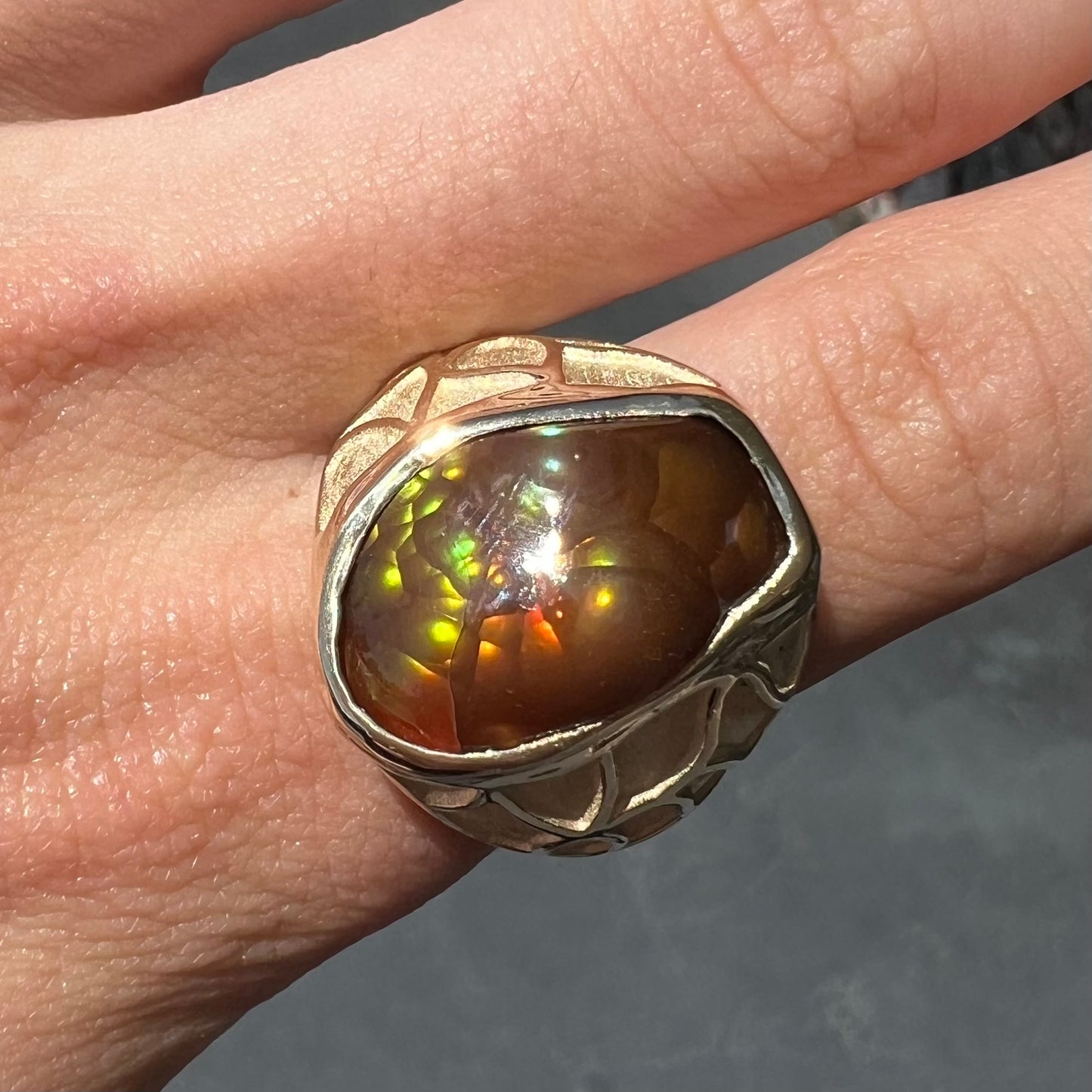 A men's heavy yellow gold ring mounted with a Mexican fire agate stone.  The shank of the ring is textured.