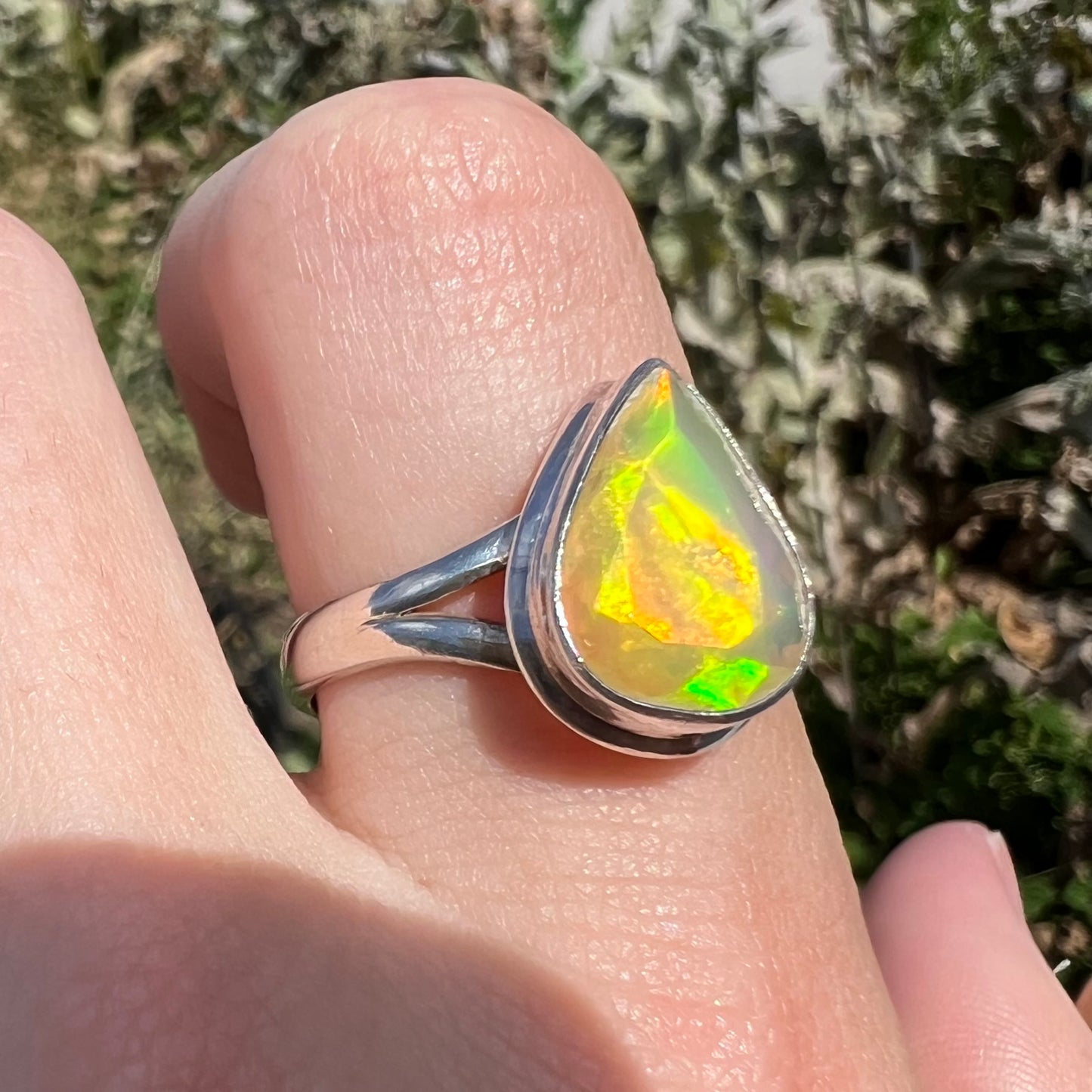 A unisex sterling silver ring set with a faceted pear shaped Ethiopian fire opal.  The opal plays orange, red, and green colors.