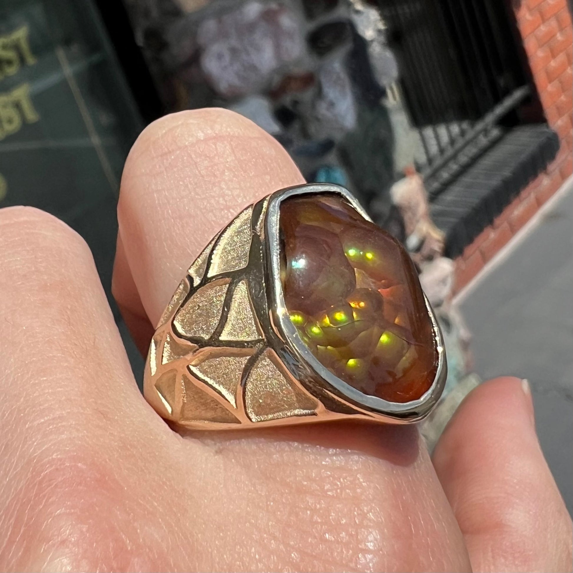 A men's heavy yellow gold ring mounted with a Mexican fire agate stone.  The shank of the ring is textured.