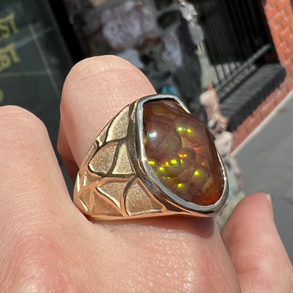 A men's heavy yellow gold ring mounted with a Mexican fire agate stone.  The shank of the ring is textured.