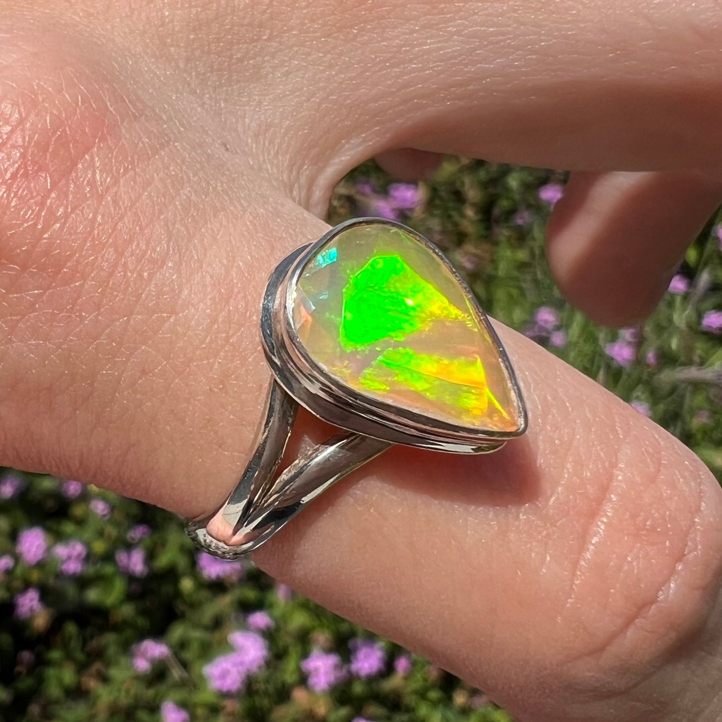 A unisex sterling silver ring set with a faceted pear shaped Ethiopian fire opal.  The opal plays orange, red, and green colors.