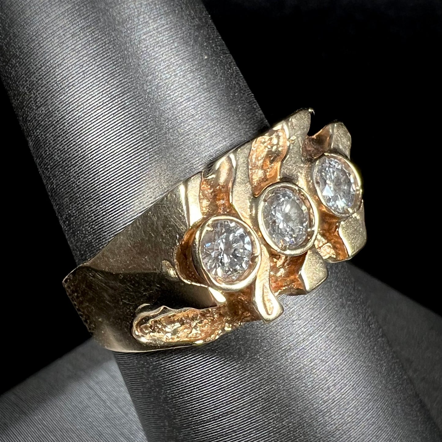 A men's yellow gold ring set with three round brilliant cut diamonds.  There are scratches along the shank.