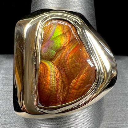 A heavy, yellow gold men's ring mounted with a Mexican fire agate stone.  The fire agate has orange, green, red, and purple colors.