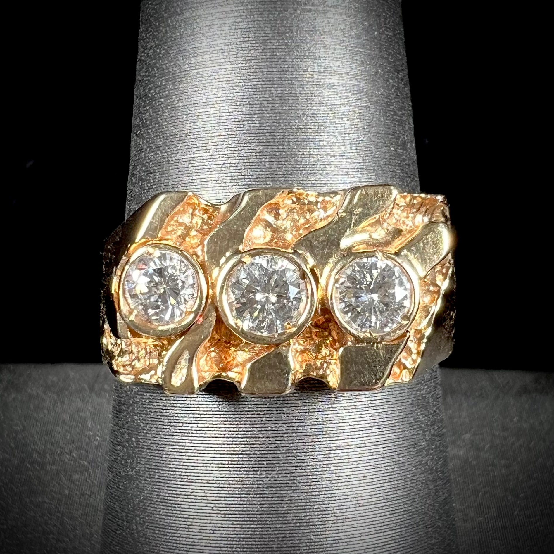 A men's yellow gold ring set with three round brilliant cut diamonds.  There are scratches along the shank.