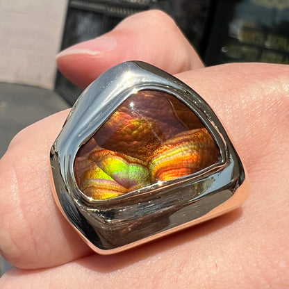 A heavy, yellow gold men's ring mounted with a Mexican fire agate stone.  The fire agate has orange, green, red, and purple colors.