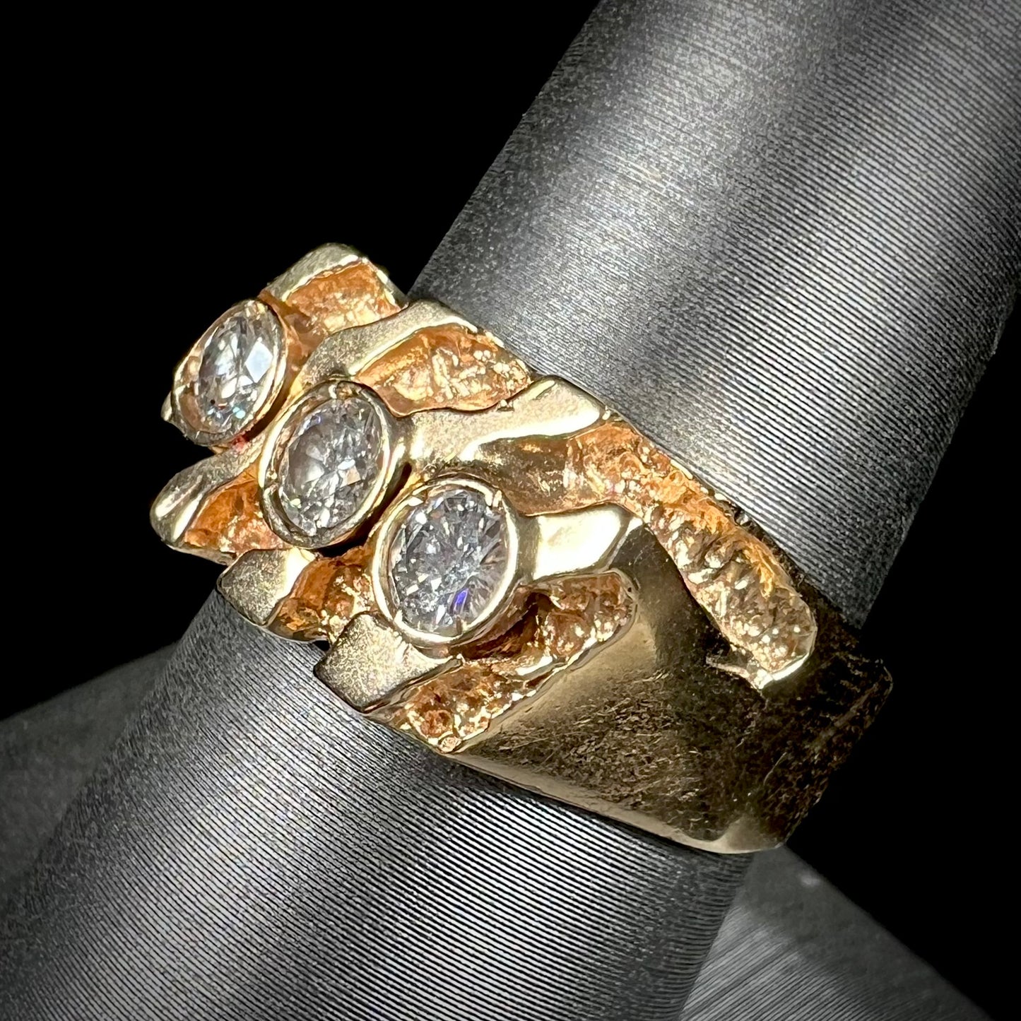 A men's yellow gold ring set with three round brilliant cut diamonds.  There are scratches along the shank.