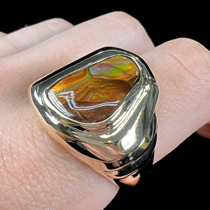 A heavy, yellow gold men's ring mounted with a Mexican fire agate stone.  The fire agate has orange, green, red, and purple colors.