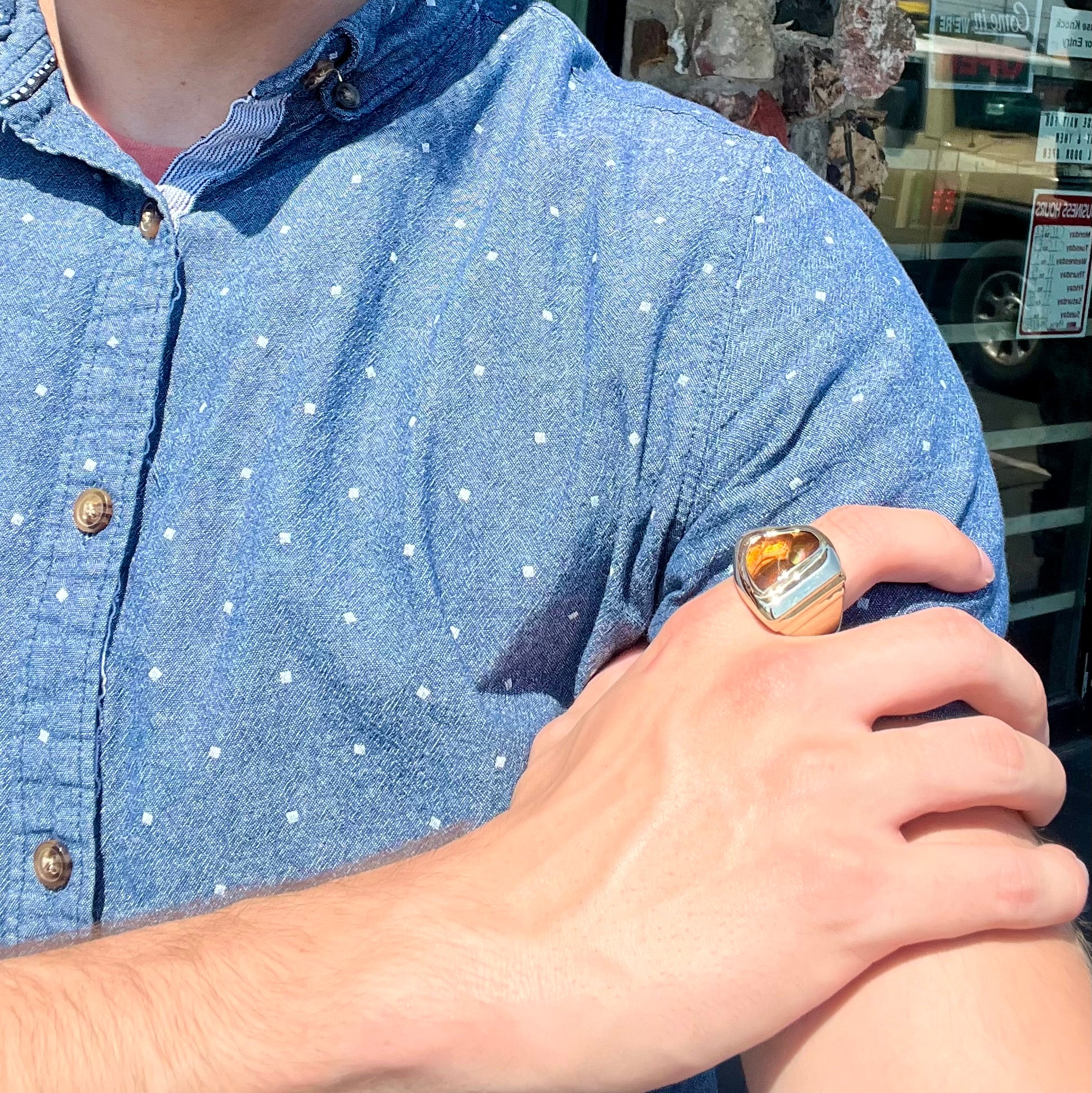 A heavy, yellow gold men's ring mounted with a Mexican fire agate stone.  The fire agate has orange, green, red, and purple colors.