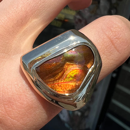 A heavy, yellow gold men's ring mounted with a Mexican fire agate stone.  The fire agate has orange, green, red, and purple colors.