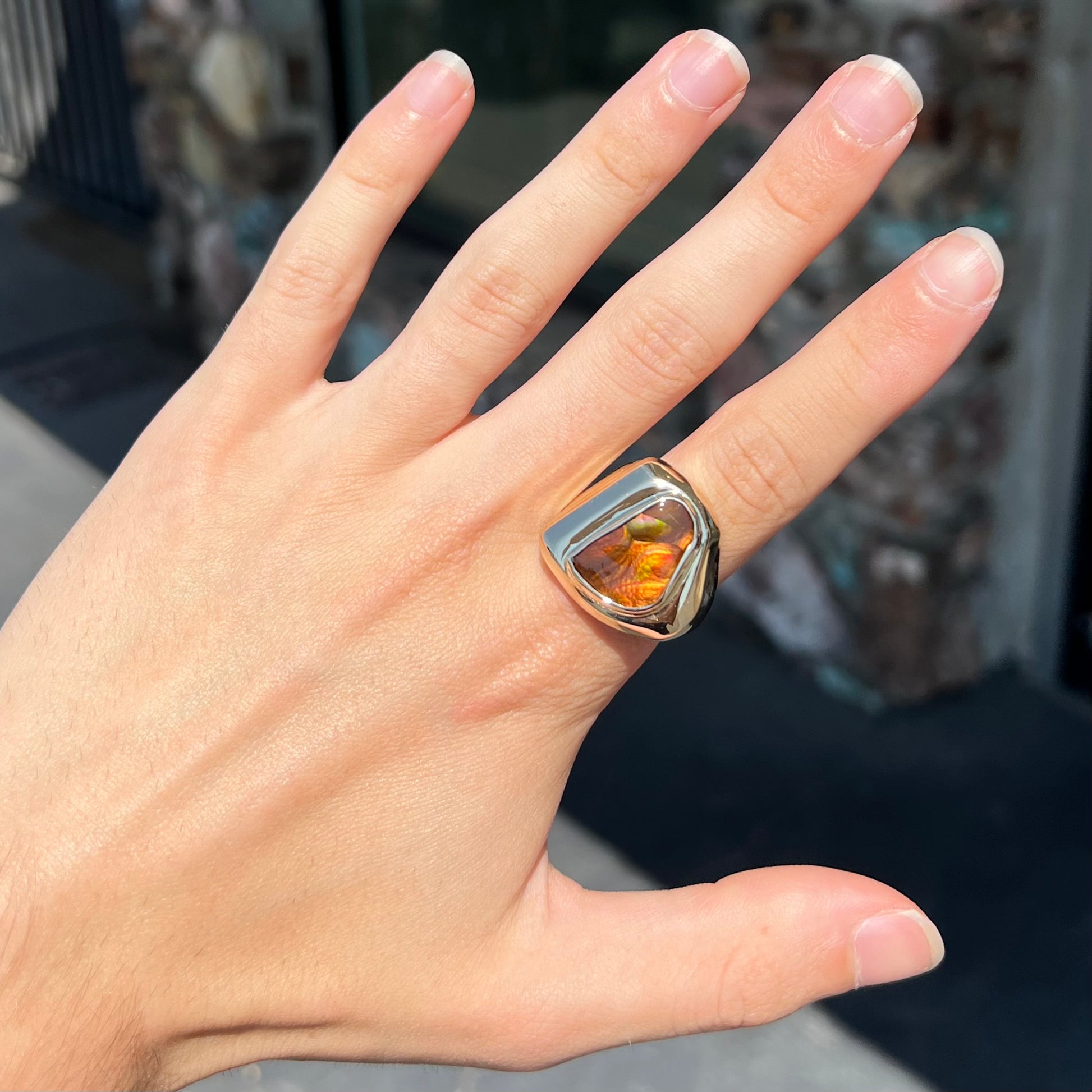 A heavy, yellow gold men's ring mounted with a Mexican fire agate stone.  The fire agate has orange, green, red, and purple colors.