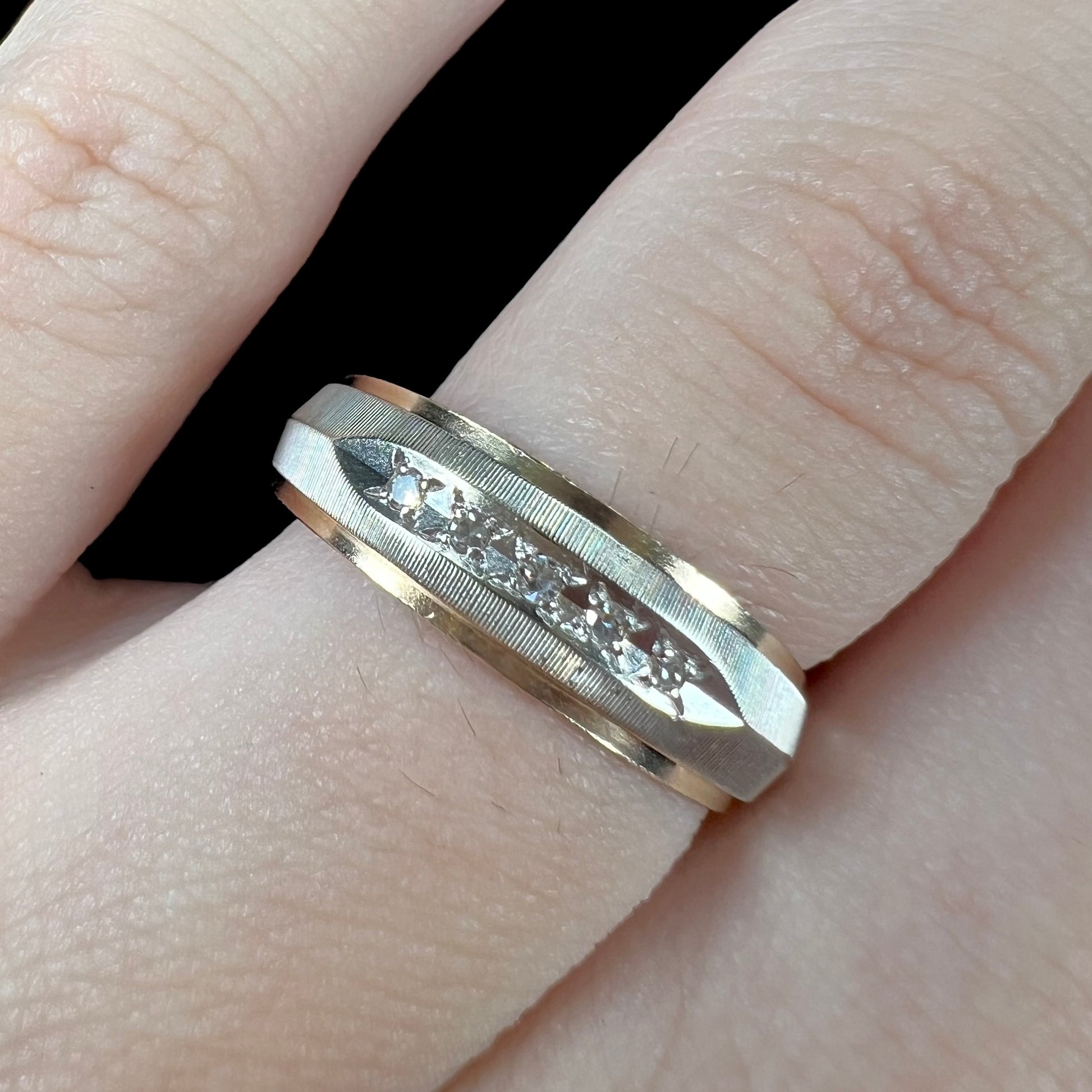 A unisex, two-tone white and yellow gold diamond wedding band.  The white gold is textured.