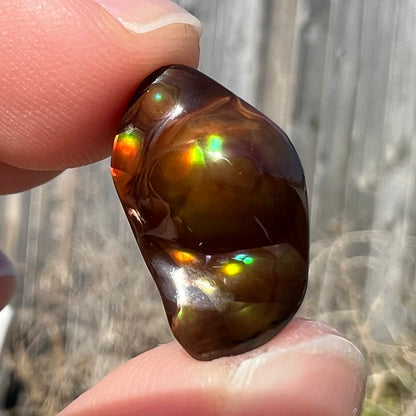 A loose fire agate stone.  The stone has a rainbow of metallic iridescence.