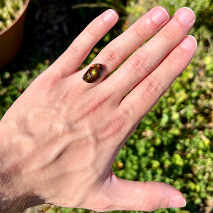 A loose fire agate stone.  The stone has a rainbow of metallic iridescence.