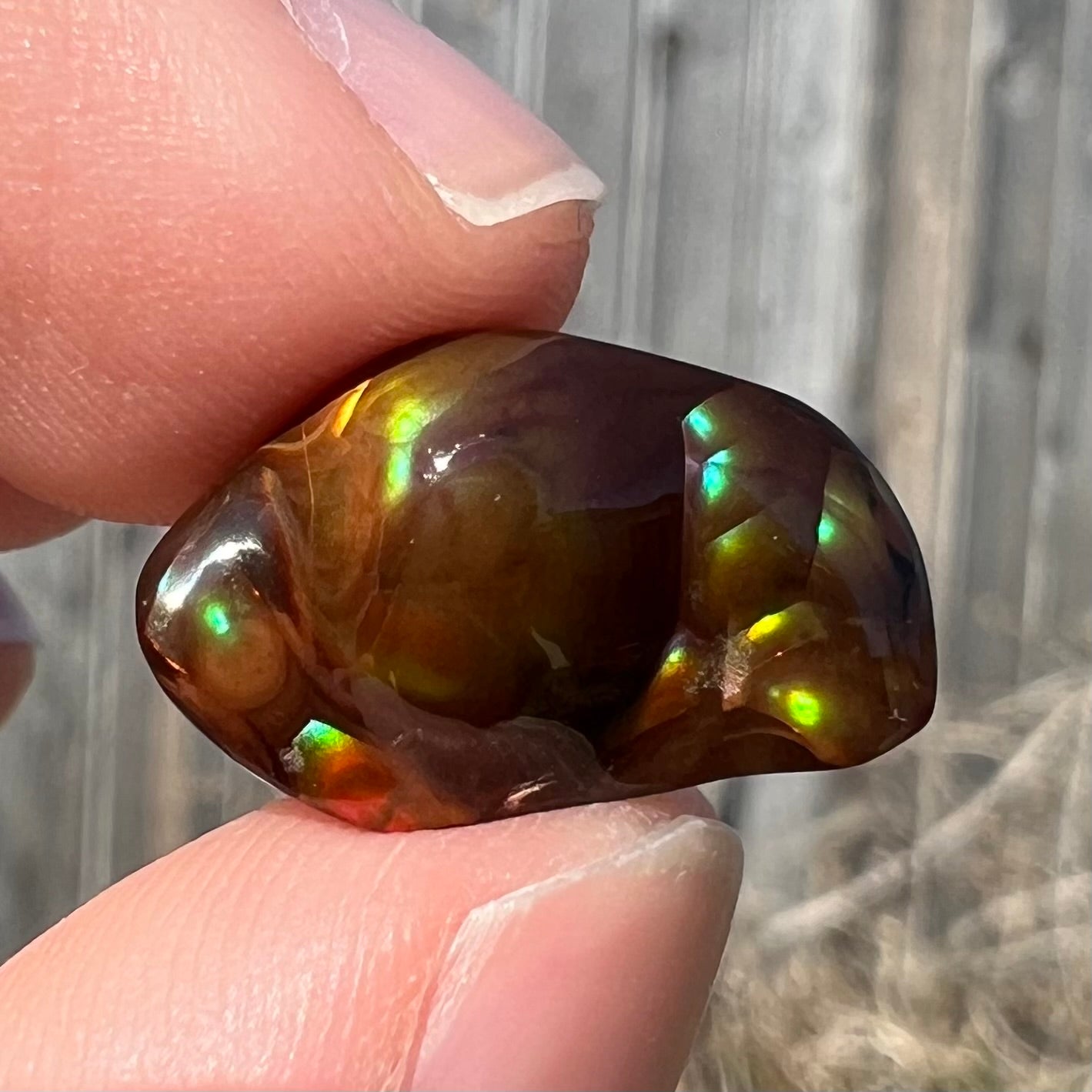 A loose fire agate stone.  The stone has a rainbow of metallic iridescence.