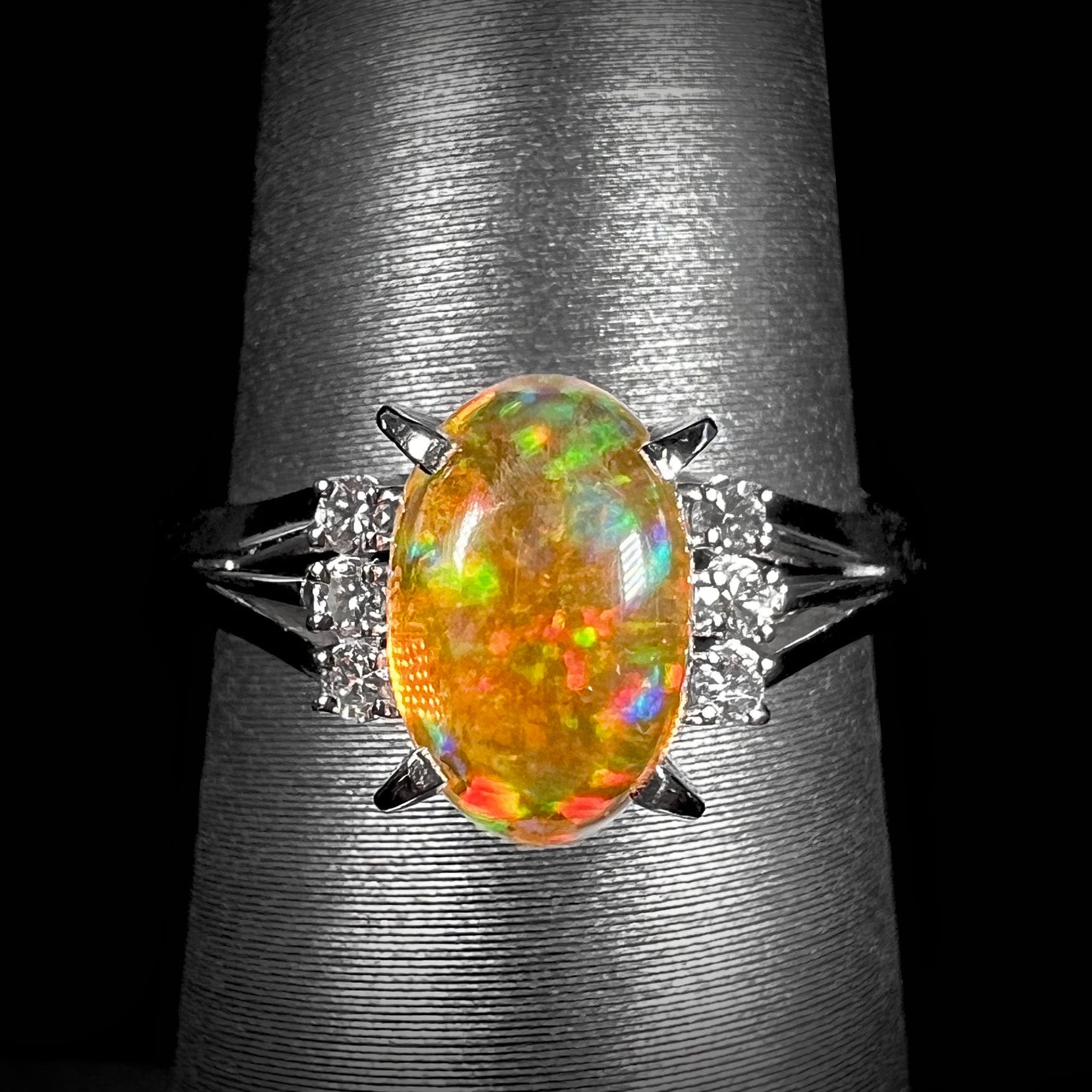 A platinum filigree and diamond-accented Mexican fire opal ring.  The opal is orange with green fire.