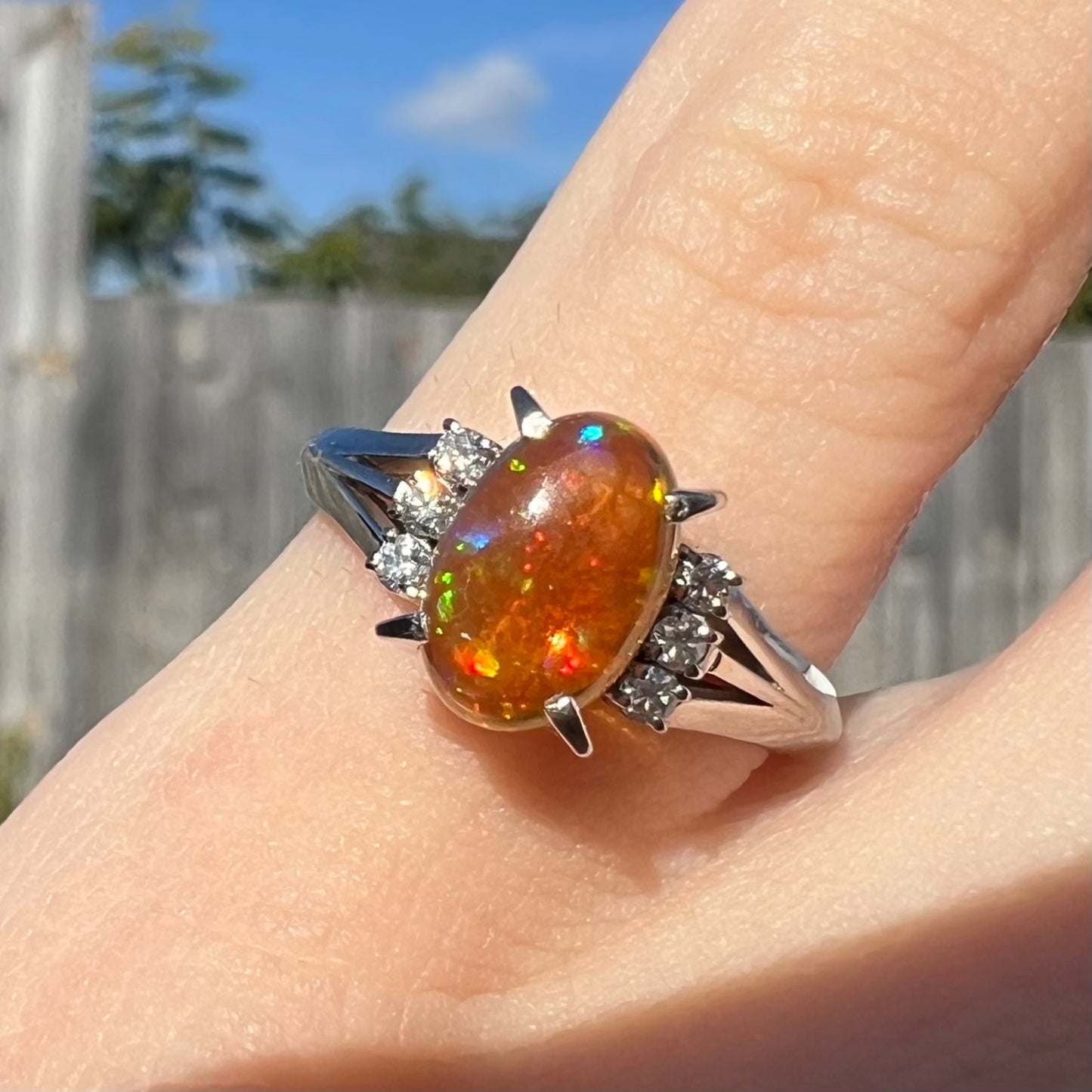 A platinum filigree and diamond-accented Mexican fire opal ring.  The opal is orange with green fire.