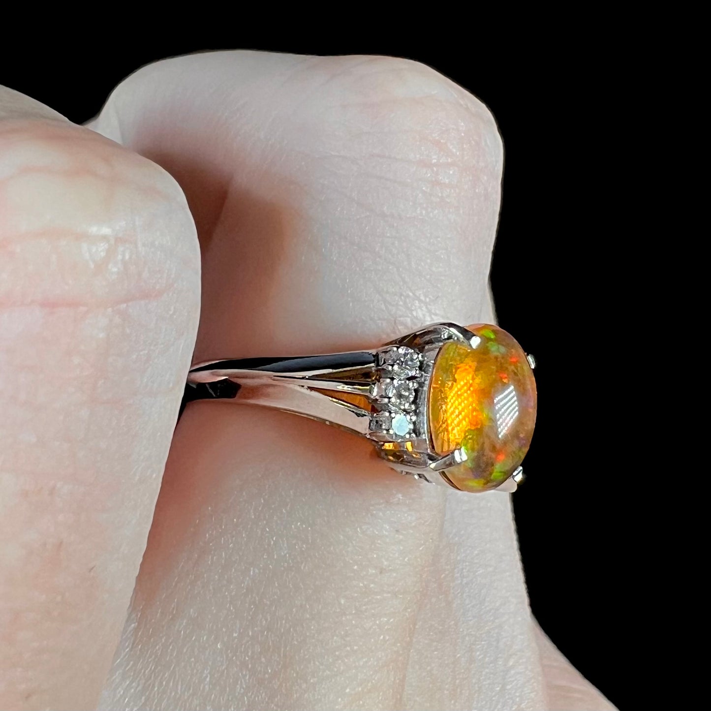 A platinum filigree and diamond-accented Mexican fire opal ring.  The opal is orange with green fire.