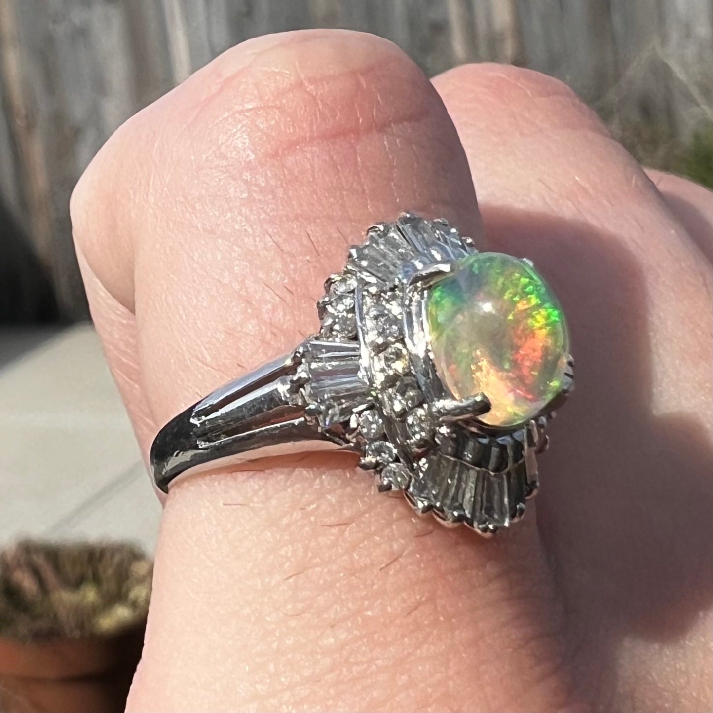 A platinum ring mounted with a Mexican fire opal and baguette cut diamond accents.