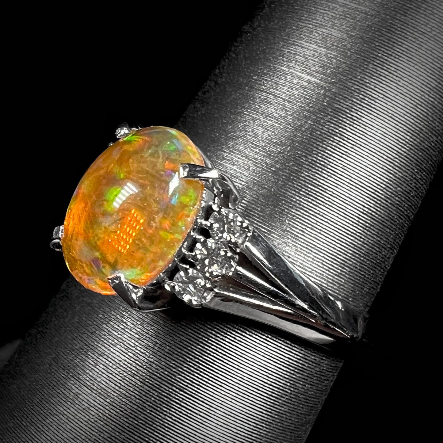 A platinum filigree and diamond-accented Mexican fire opal ring.  The opal is orange with green fire.