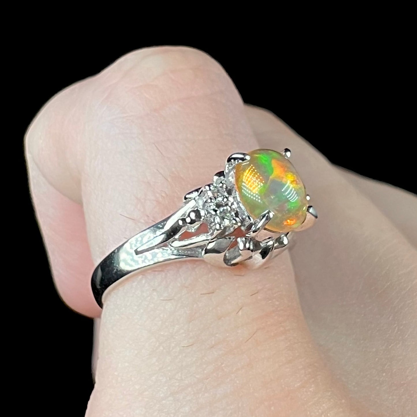 A platinum, diamond accented ring prong-set with an oval cabochon cut Mexican fire opal.