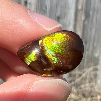 A brightly reflective Mexican fire agate cabochon.  The stone has a strong green iridescence.