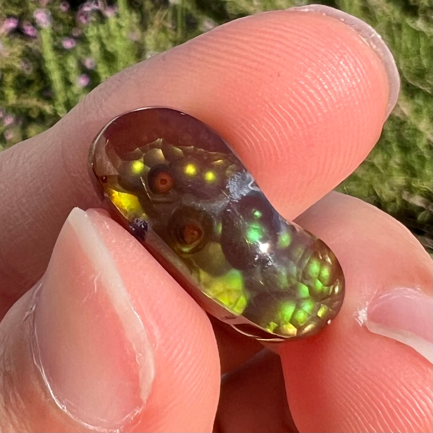 A loose, cabochon cut fire agate gemstone.  The stone resembles a foot with a green heel and yellow toes.