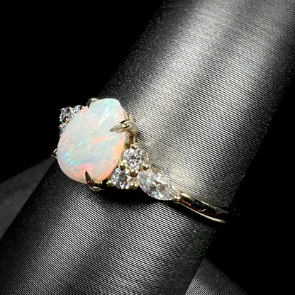 A dainty, pear shaped opal ring mounted in yellow gold with moissanite accents.