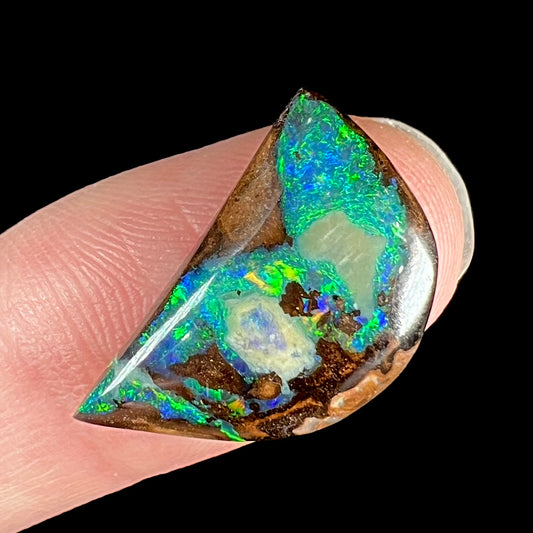 A loose, freeform shaped boulder opal with green and blue multicolor fire from Australia.