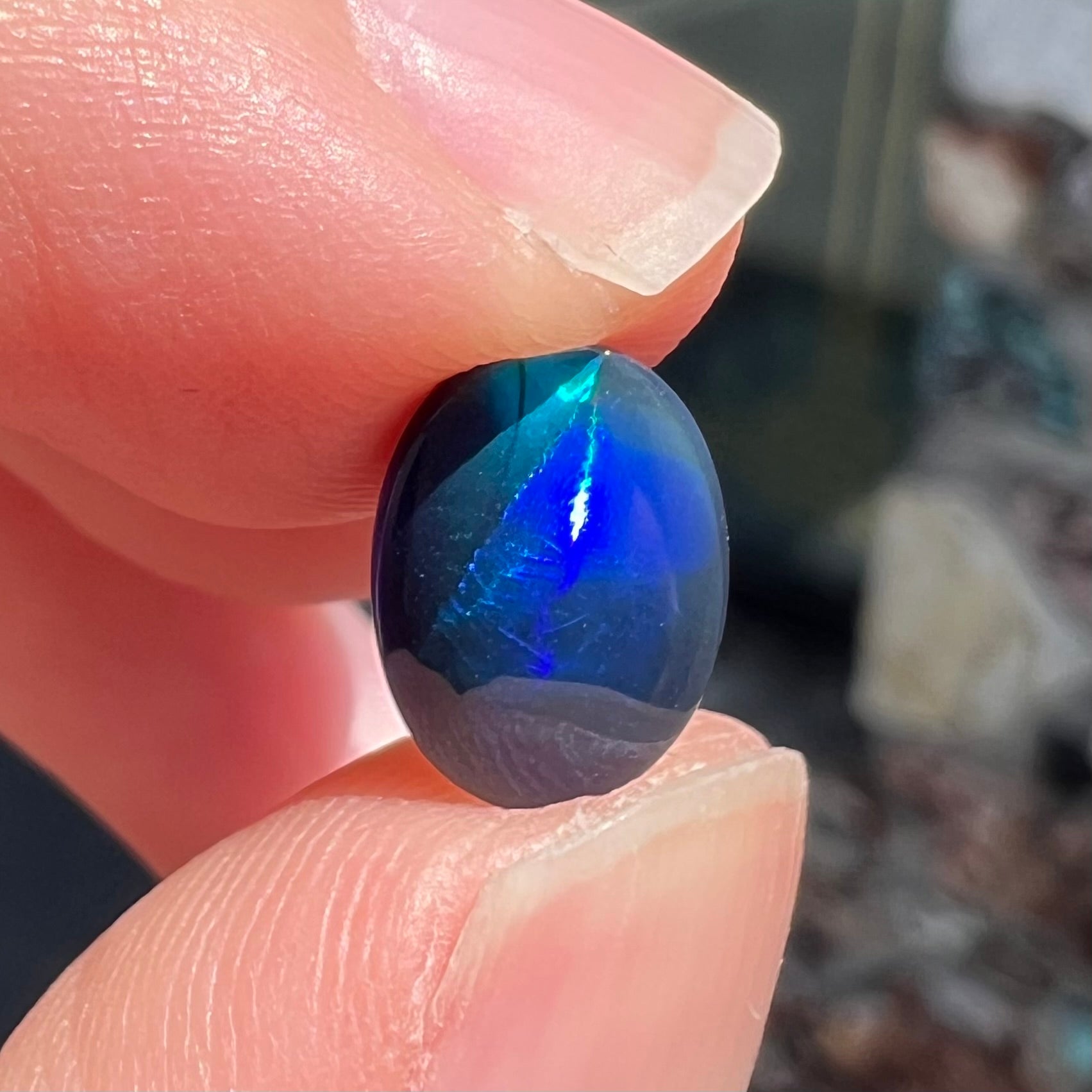 A loose, oval cabochon cut black opal from Lightning Ridge, Australia.  The opal has an N2 body tone.