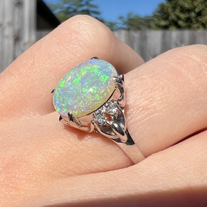 An Australian crystal opal engagement ring set with diamonds in a platinum filigree mounting.  The opal plays green/blue colors and has a crack.