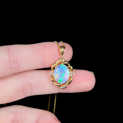 An 18 karat yellow gold diamond-accented necklace mounted with a green and blue Lightning Ridge crystal opal.