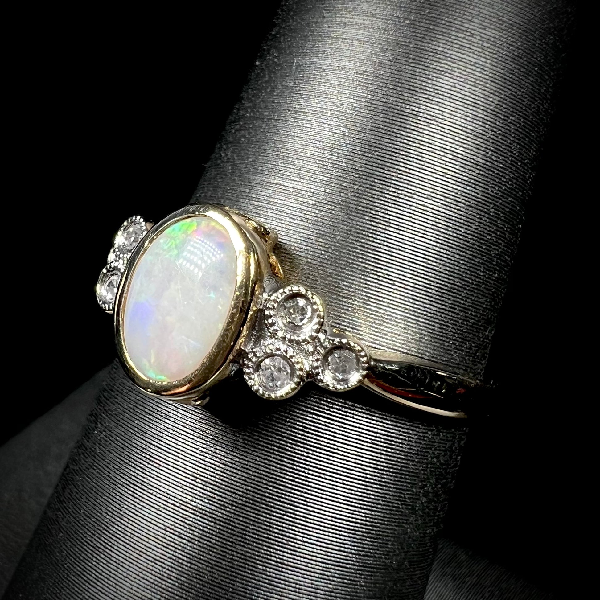 A ladies' yellow gold opal ring.  Three diamonds are set on each side of the opal.  Two rubies are set under the opal.