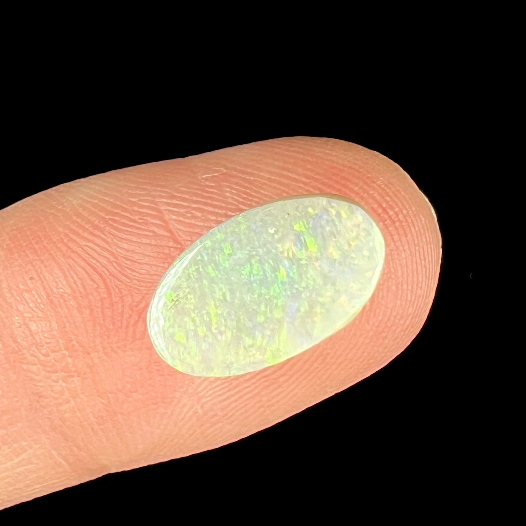 A loose, oval cabochon cut white opal stone from Coober Pedy, Australia.