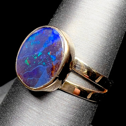 A ladies' split shank natural, Lightning Ridge, Australian black opal solitaire ring in yellow gold.