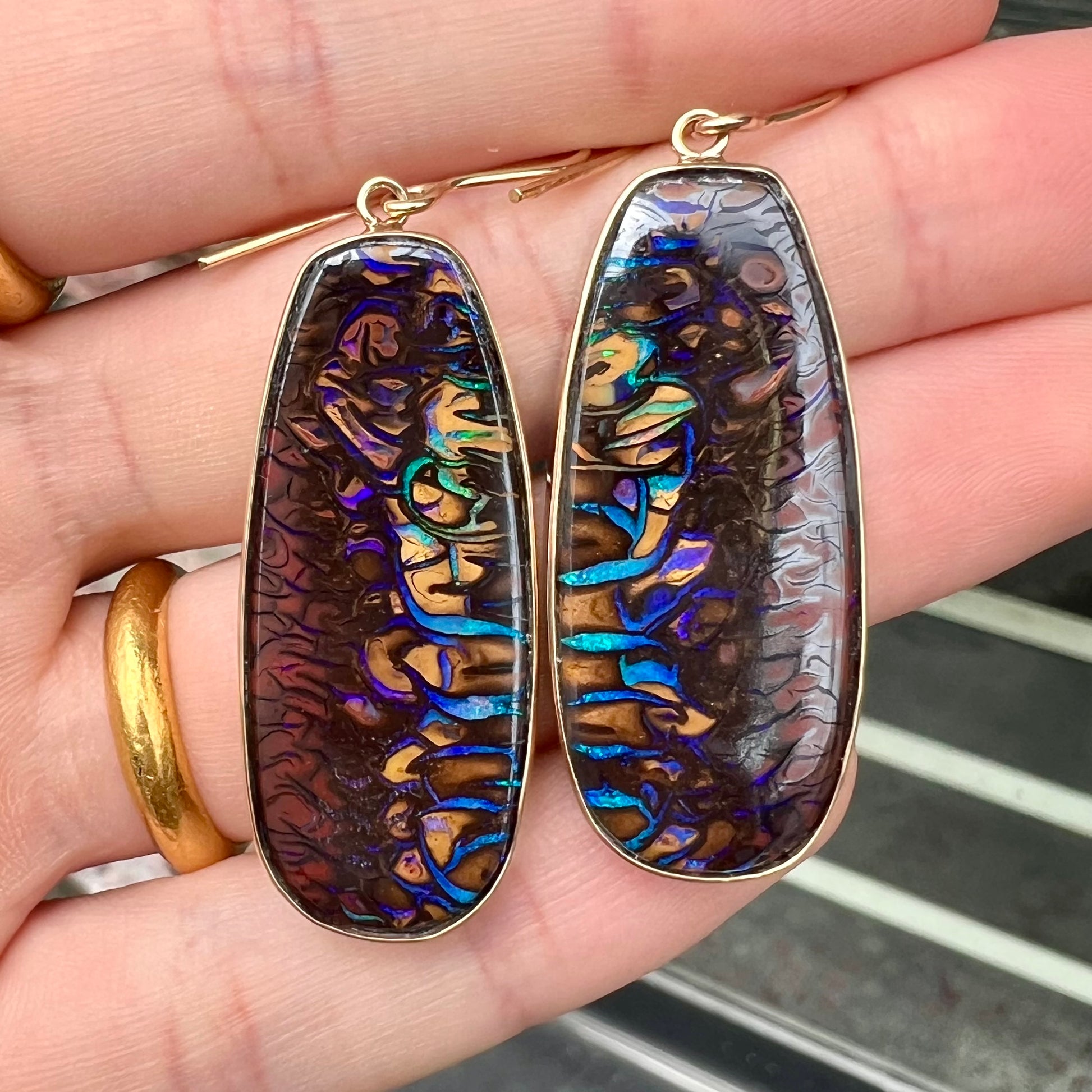 A matched pair of yellow gold patterned boulder opal dangle earrings.  The opals are from Koroit, Australia.