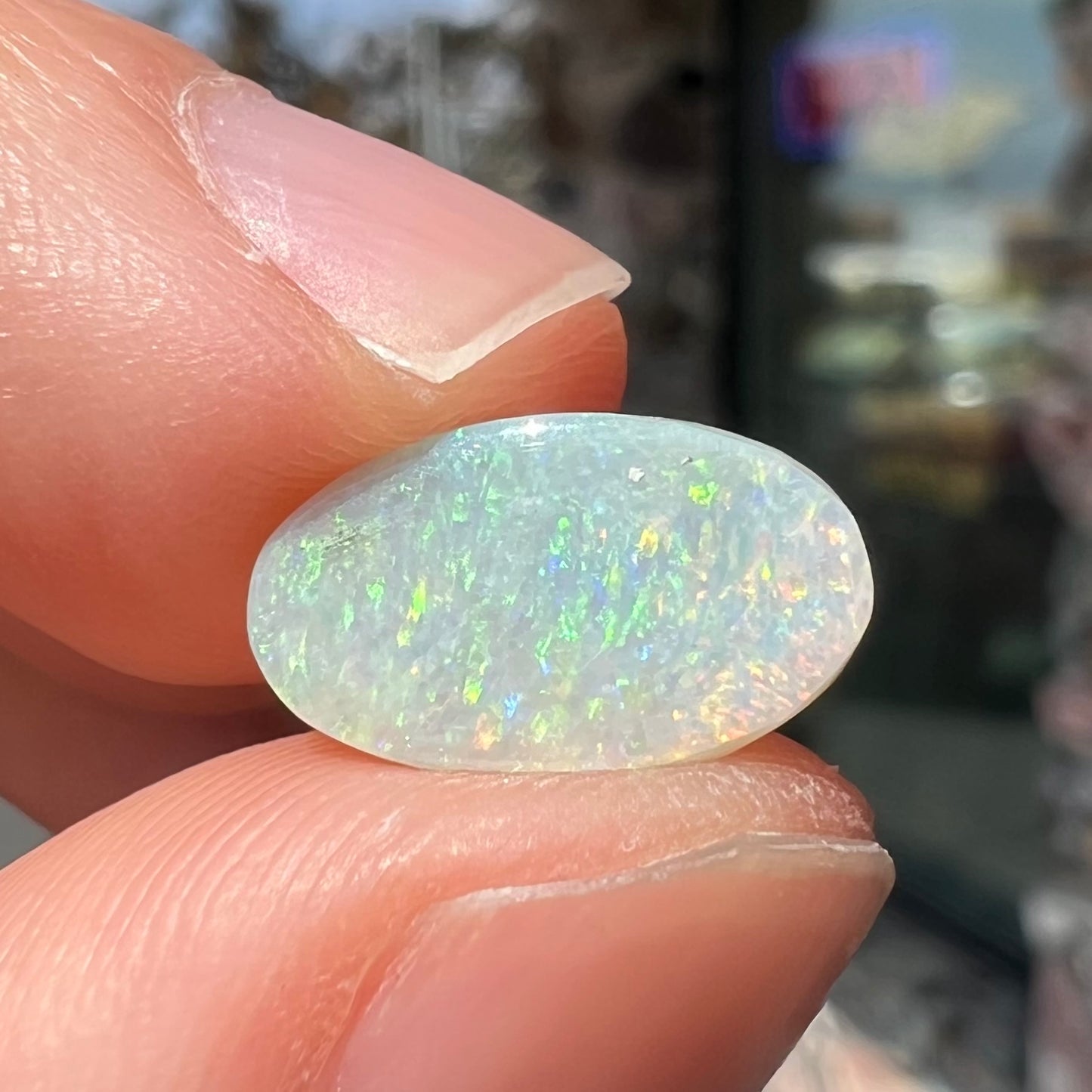 A loose, oval cabochon cut white opal stone from Coober Pedy, Australia.