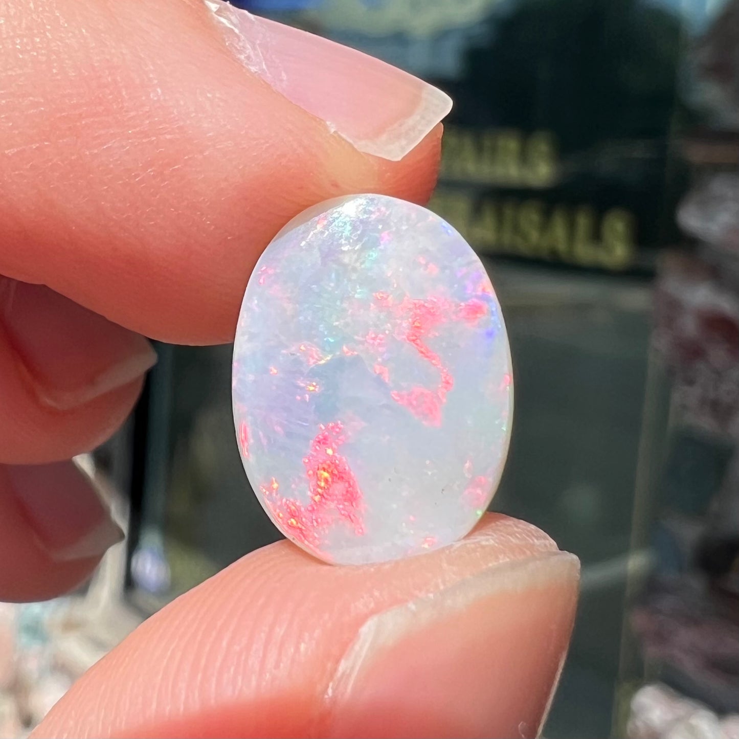 A loose oval cut opal stone from Lightning Ridge, Australia.  The opal shines pinkish red colors.